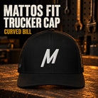 Black Mattos Fit trucker cap with a curved bill, mesh sides and white embroidered M.